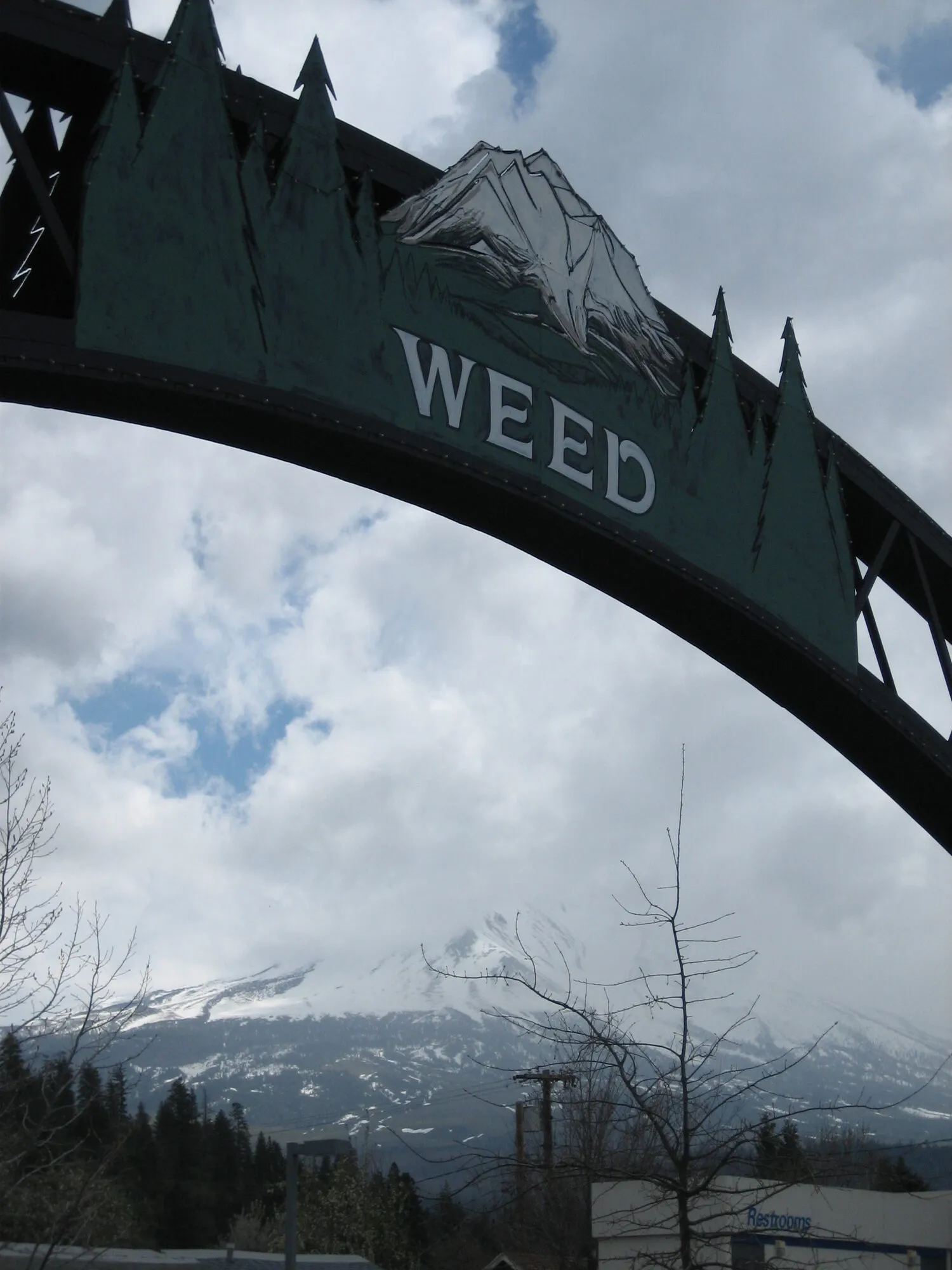 The Weed, California arch sign with Mount Shasta in the clouds behind it
